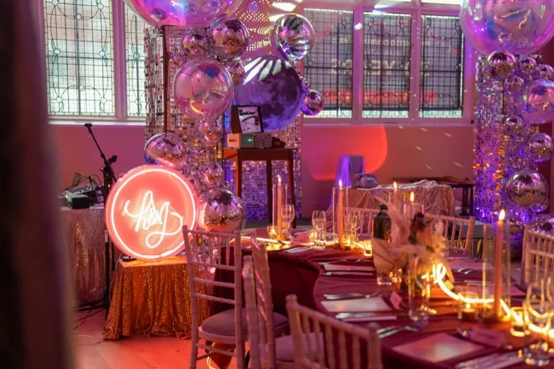 Table settings with neon signage and disco balls at a styled event