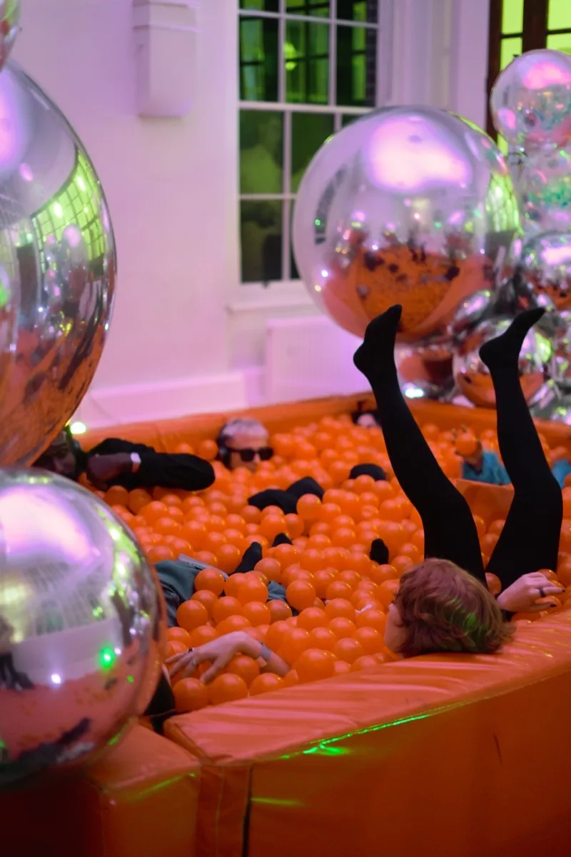 Guests in an orange ball pit with disco balls at Richmond Barracks event