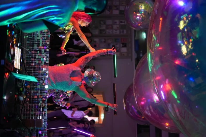 Performer dancing under neon lights at Richmond Barracks party
